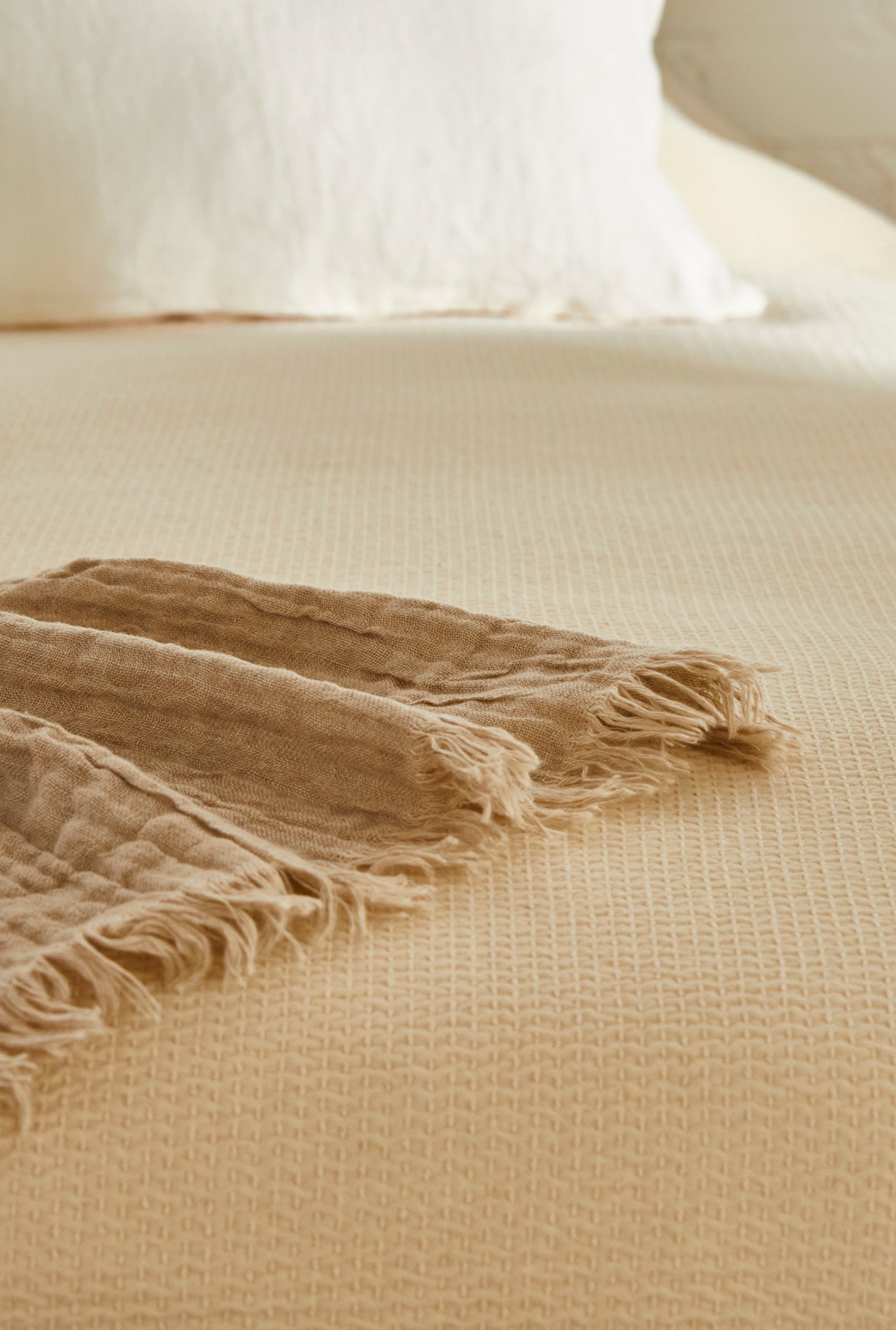 Lähikuva luonnonvalkoisen Polku-päiväpeiton tekstuurista ja tikkauksesta.