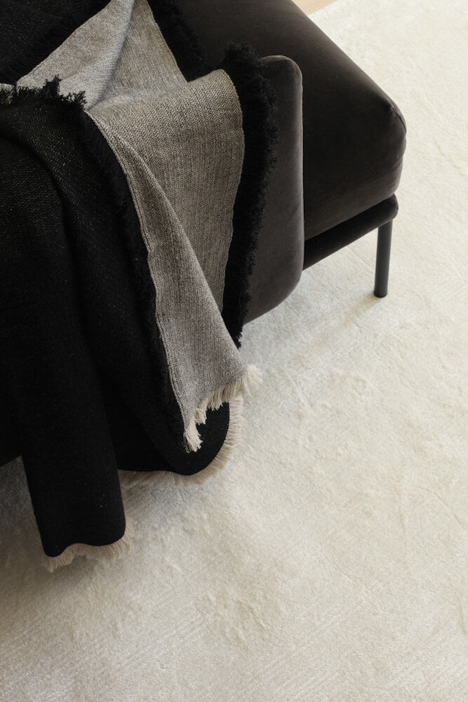 Roots Living Pile Viscose valkoinen viskoosimatto mustan samettisohvan alla. Roots Living Pile Viscose rug in white.