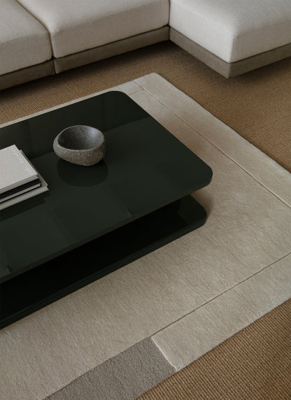 Vaalea Geo one -villamatto tummanvihreän Profondo sohvapöydän alla. Geo One wool carpet under the Profondo table in dark green.