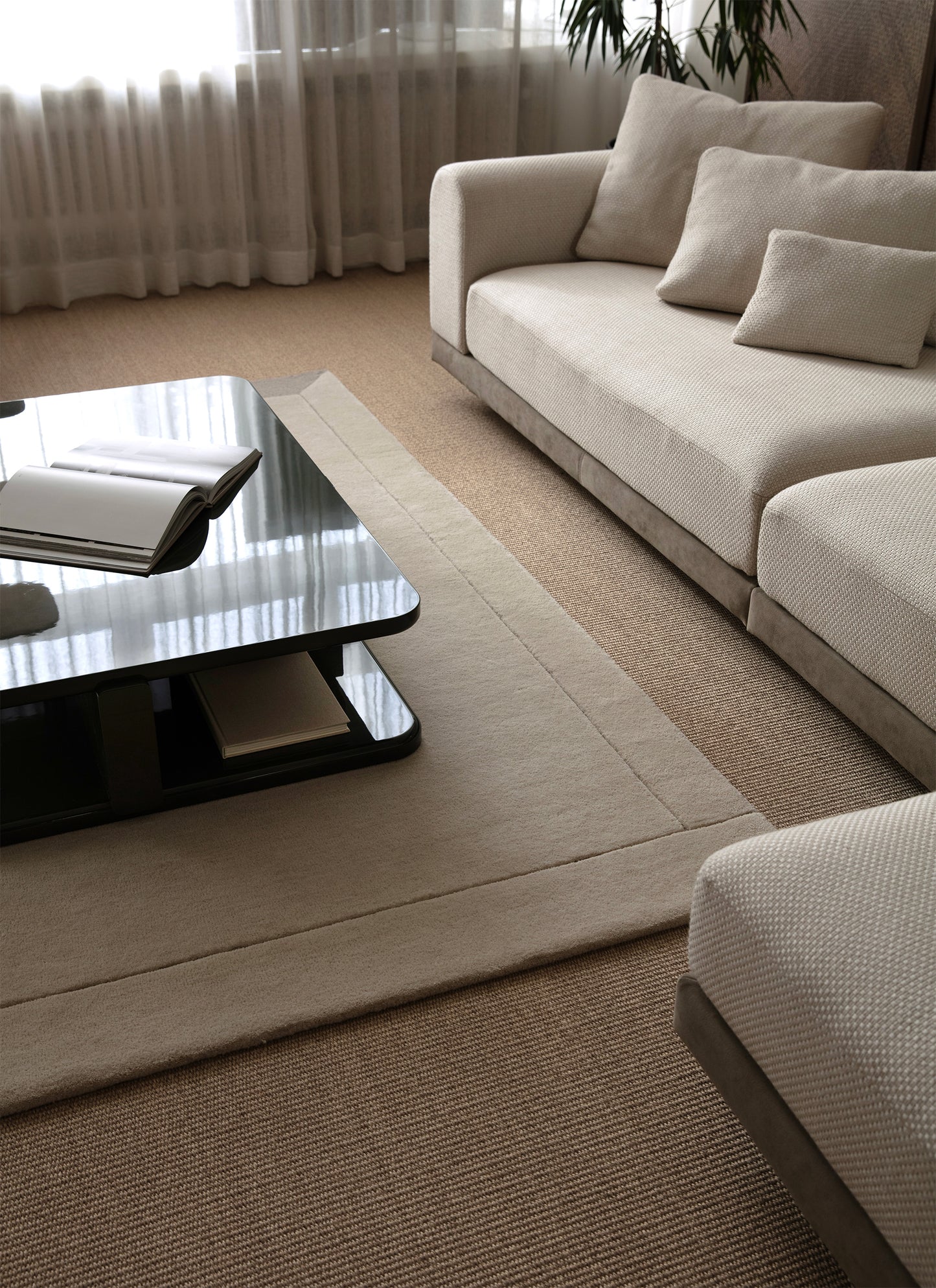 Vaalea sohva ja vaalea Geo One -villamatto valoisassa tilassa. Sohvapöydällä avoin kirja. 