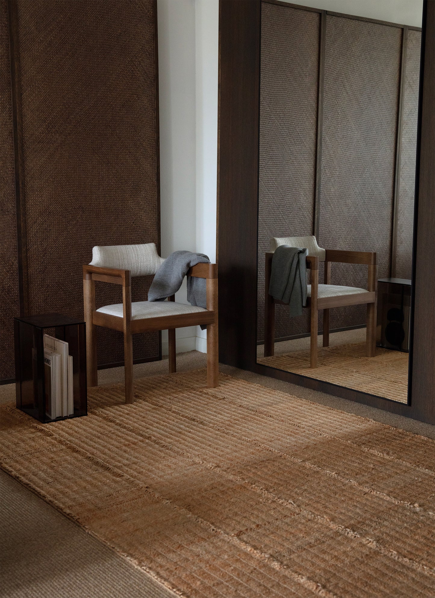 Waffle Line -hamppumattoon heijastuu valoa suuren peilin kautta. Peilistä heijastuu myös maton päällä oleva puinen tuoli.